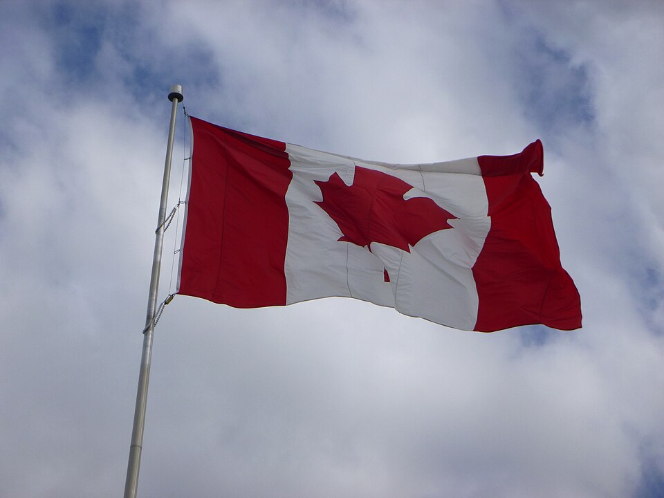 A Canadian flag in flight, illustrating its red-and-white design.